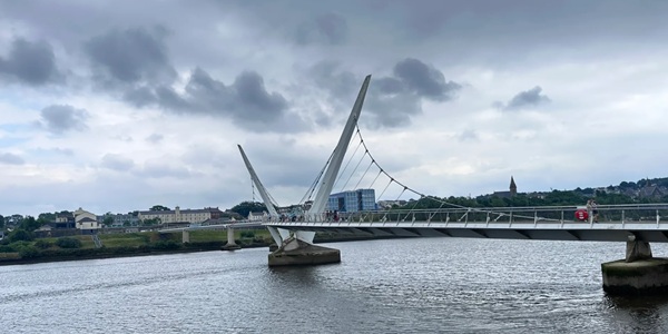 Londonderry Peace Bridge S-shaped steel footbridge spanning the River Foyle with city panorama